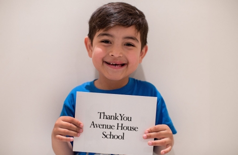 Boy holds a thank you sign to Avenue House School