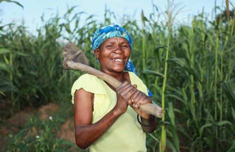 Zita smiling and holding a hoe in front of her crops