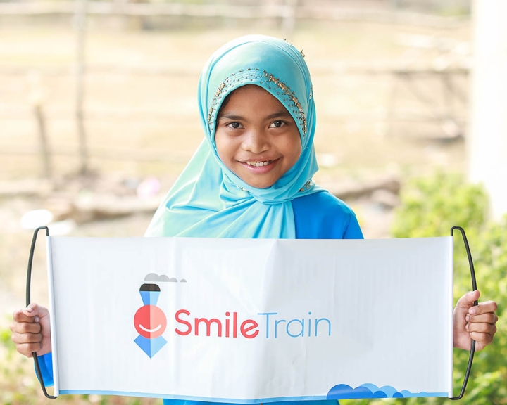 girl holds smile train sign