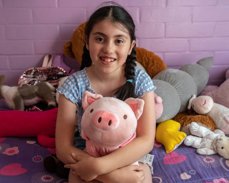 Amelie smiling and holding her plush pig after cleft surgery