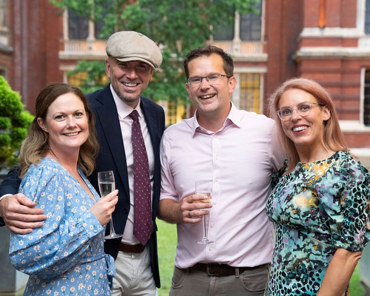 Guests smiling and holding drinks at Smile Train UK's Summer Reception